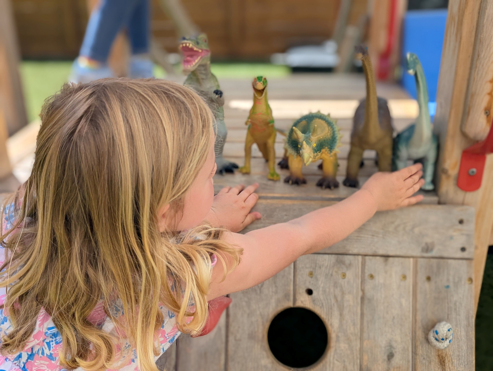 Children playing with dinosaurs on the play structure