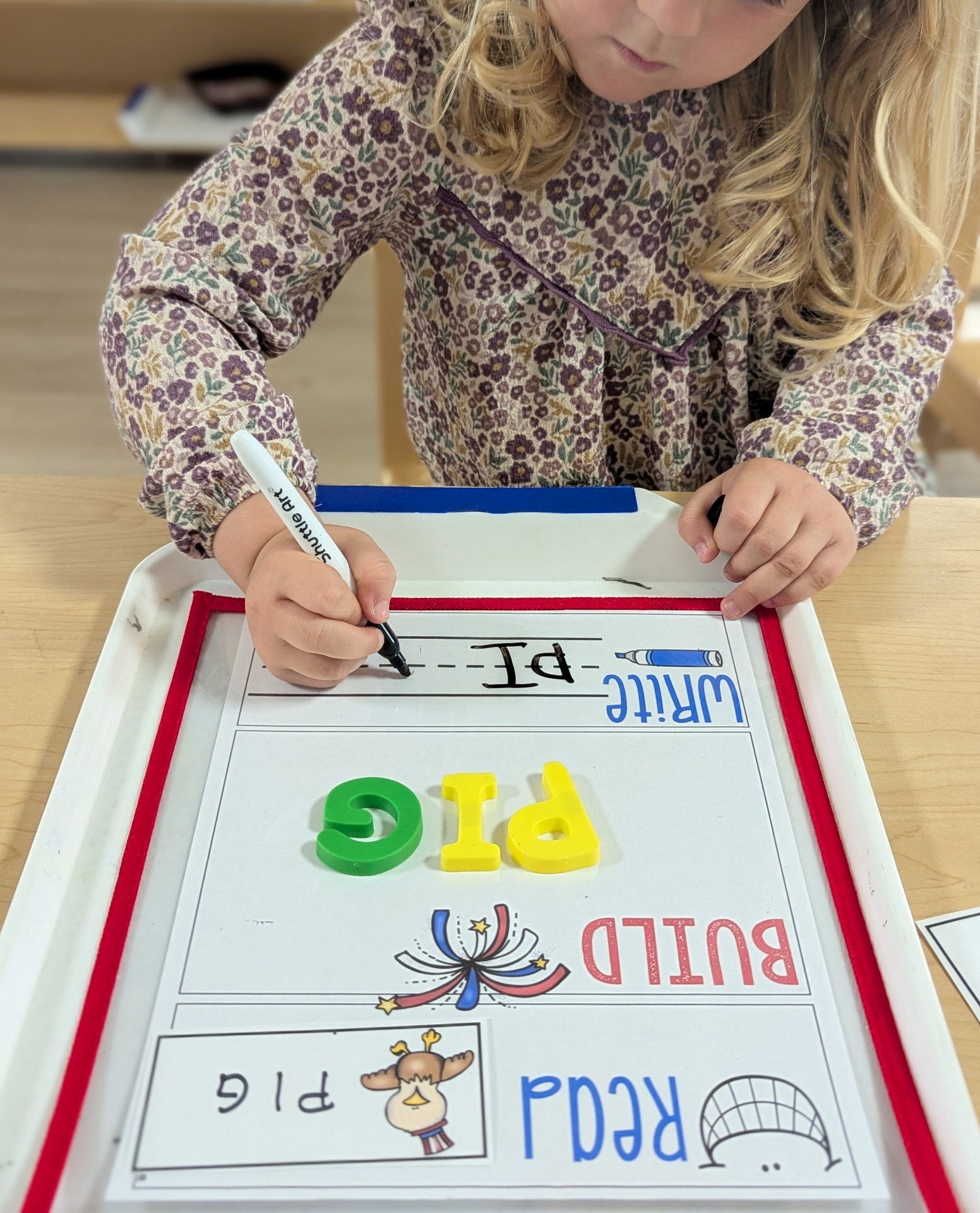 Preschooler writing letters at a tray