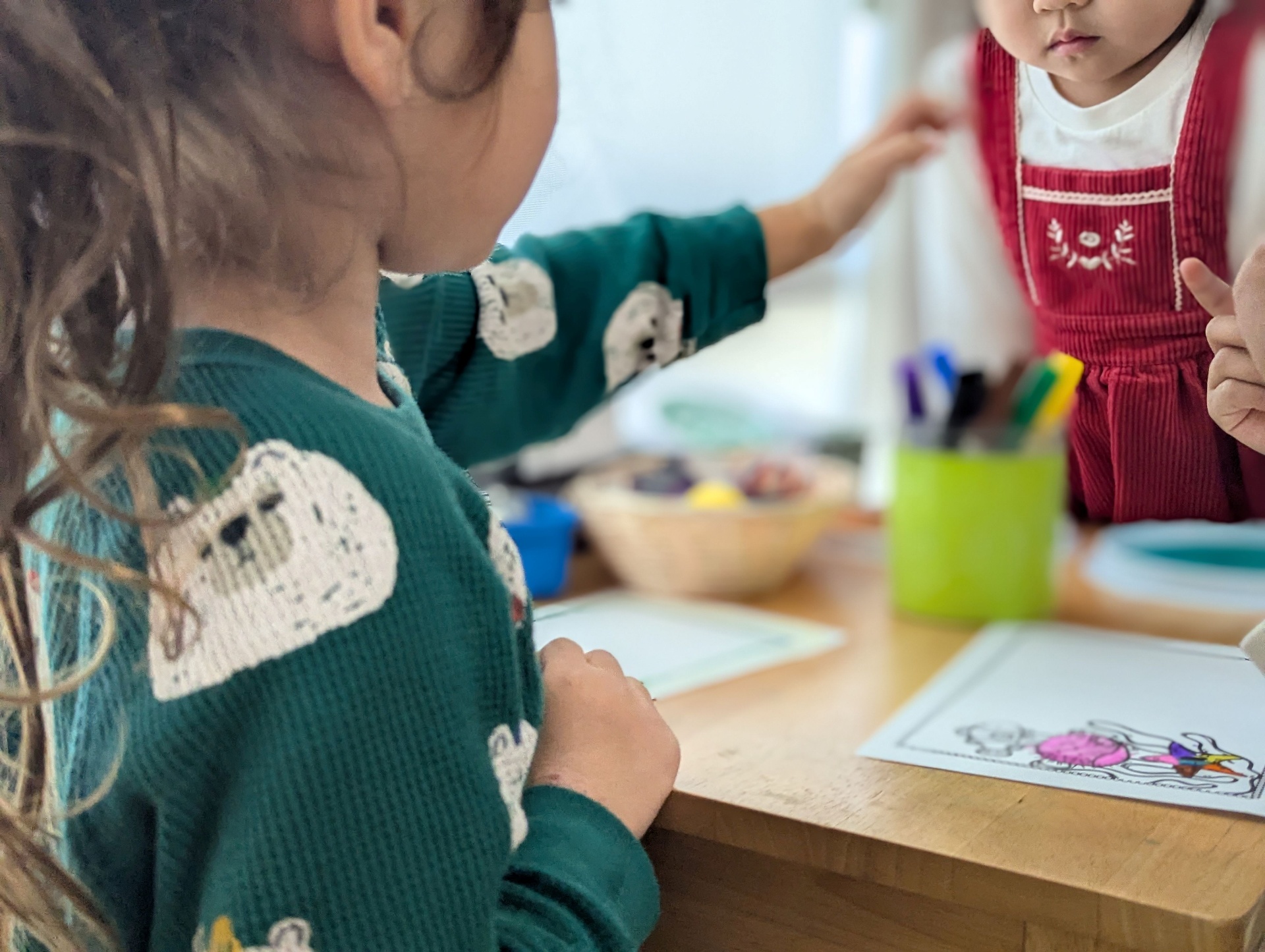 Children sharing markers at a table